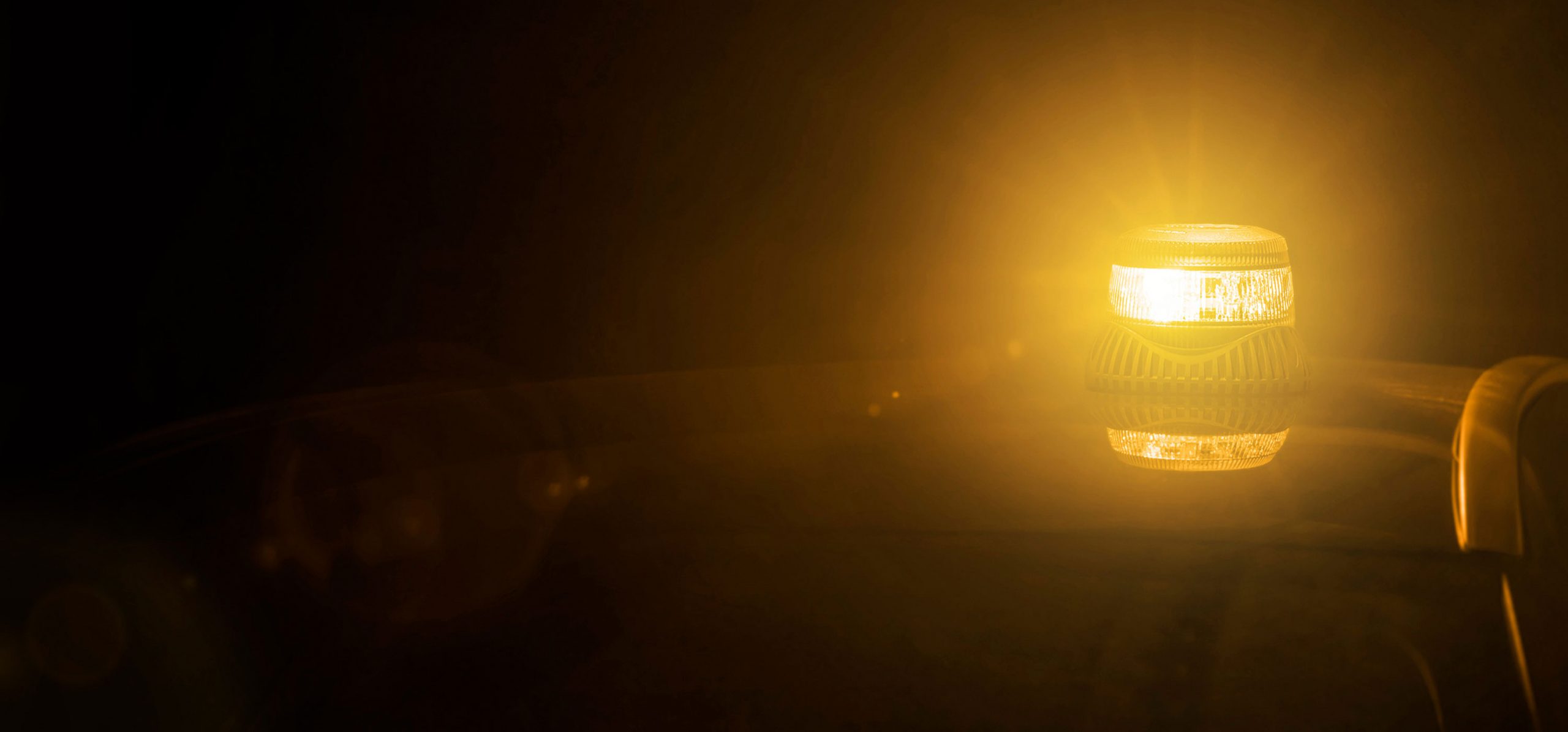 Hero Image of Amber Beacon Lit on Vehicle Roof with Dark Surroundings and Reflection