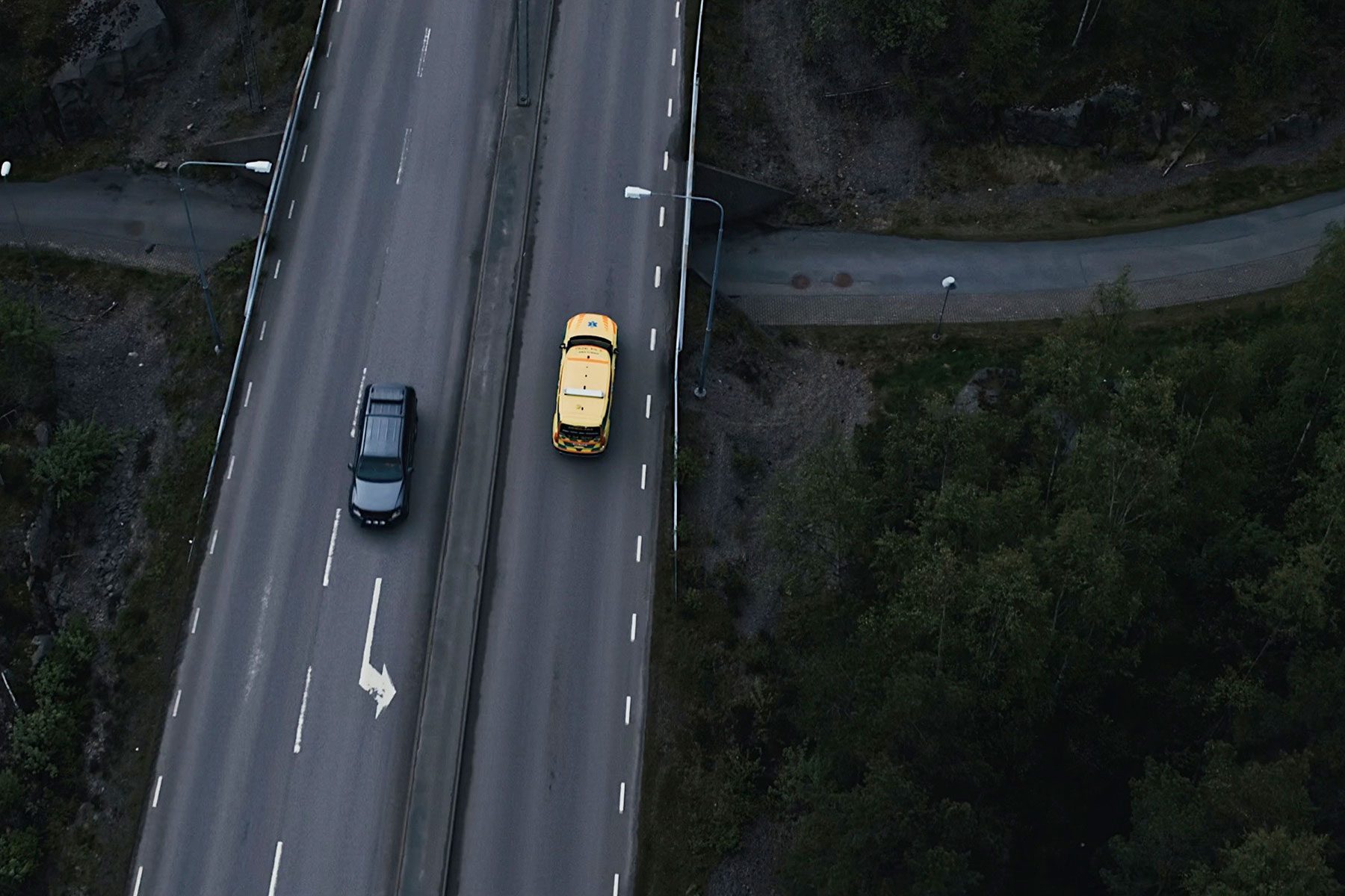 Page Image Aerial Motorway Shot Yellow Emergency Vehicle and Black Car Driving in Opposite Directions, Road and Underpass are Dark