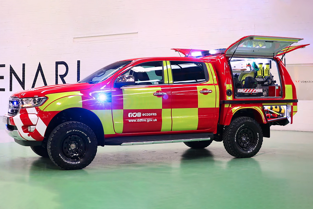 Side angled view of fire response vehicle with hatches open to show equipment and lit up inside, some emergency lights are lit including lightbar small side module and grille