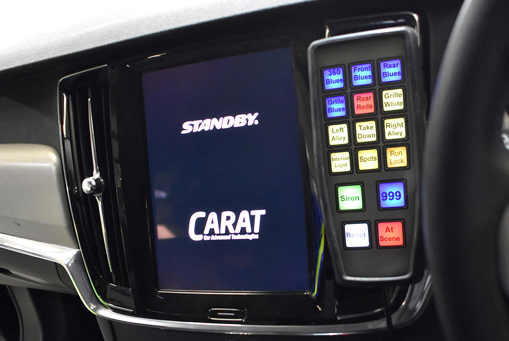 Screen displaying Standby and Carat logos on vehicle centre console with a handset with 16 lit-up multi-coloured buttons for various light and siren applications