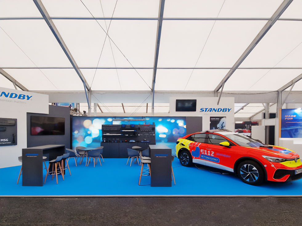 Standby Group exhibition stand with various products and seated areas, red response vehicle on righthand side, lightbar covered.