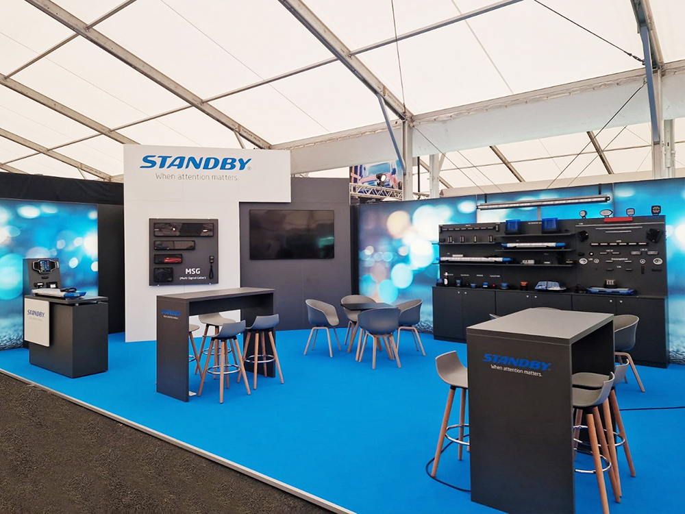 Standby Group exhibition stand with various products and seated areas.