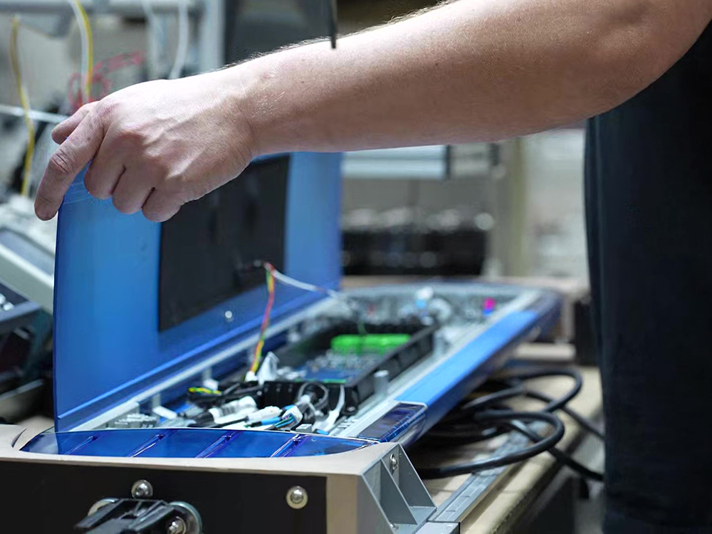 Close up of a worker opening the top of an unlit blue lightbar, revealing the components inside.