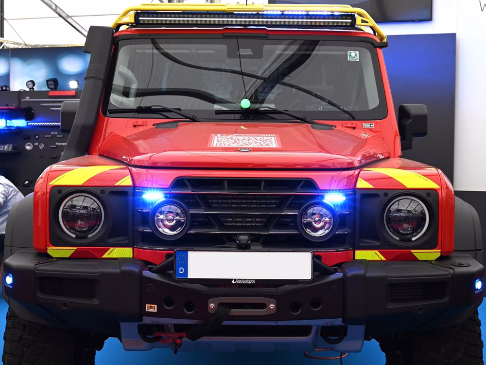 Red Fire Grenadier show vehicle with yellow livery and blue lights, closely cropped and taken from the front.