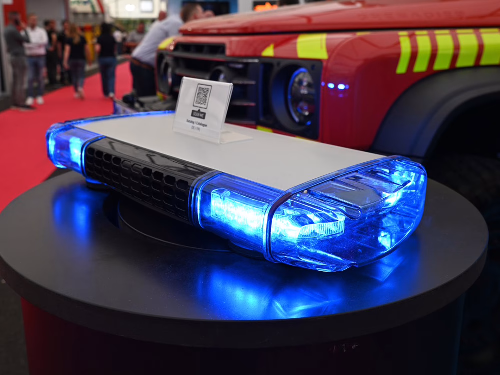 Small W3 Lightbar lit up blue with a QR code standing on top on a cylindrical black column on a trade show stand.