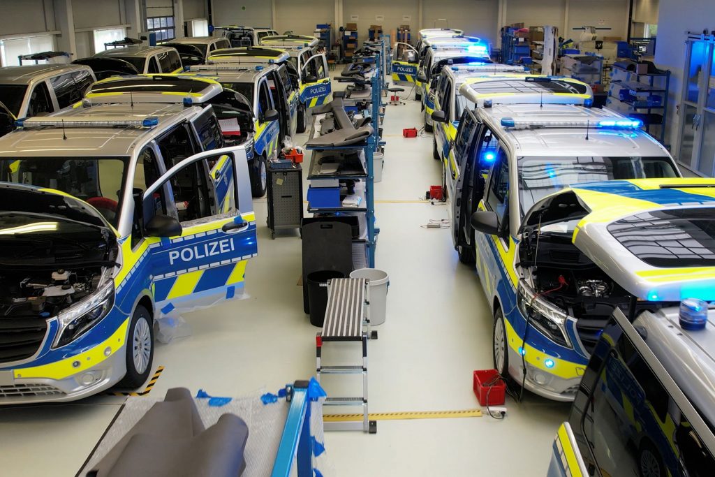 Polisbilar monteras på rad i en fabrik.