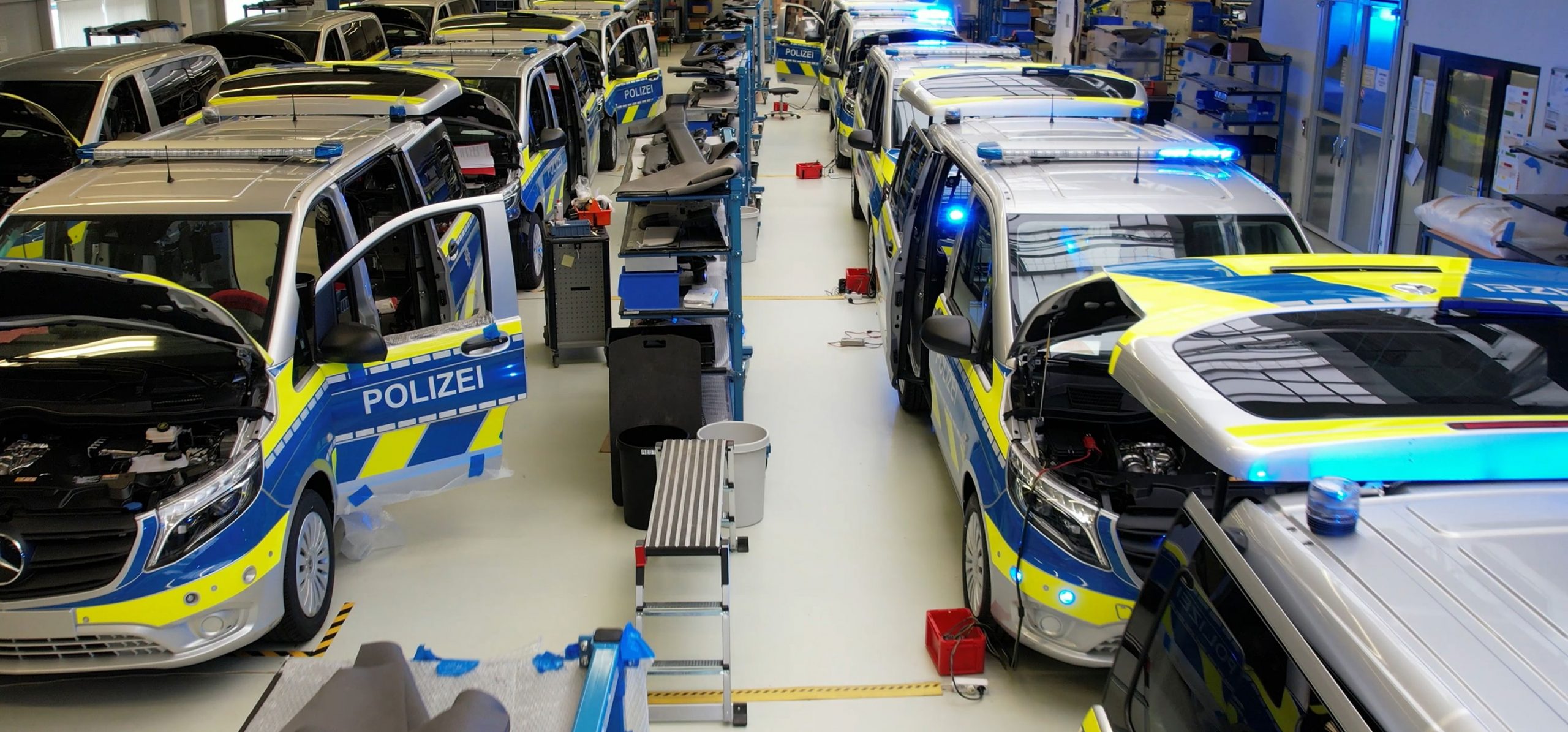 Polisbilar monteras på rad i en fabrik.