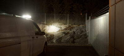 Bevakningsfordon med vitt ljus lyser upp en industriport.