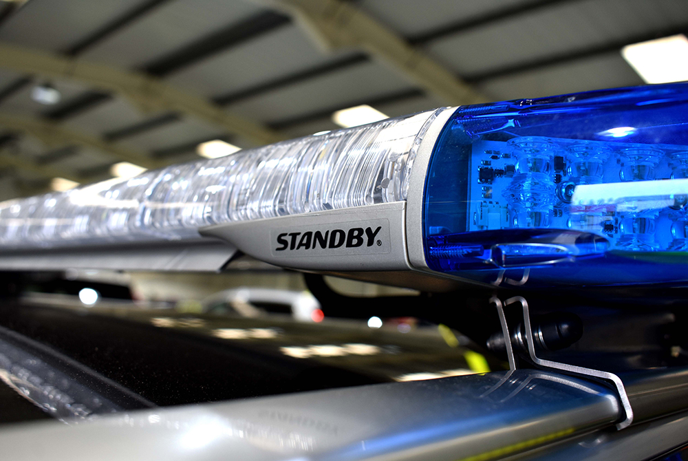 Close up of unlit lightbar with clear and blue lenses and silver housing showing Standby logo
