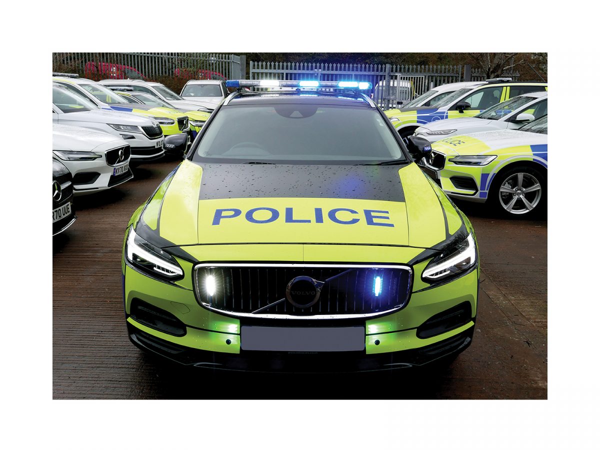 W3 Lightbar Front Blue and White LEDs Lit shown on roof of black police car with whole car in view against police parking front view