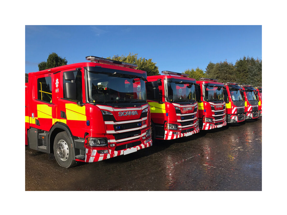 Aegis LED Lightbar In Situ Fire Fleet of 6 Scania Fire Engines Lined Up at Angle View on Wet Surface, Trees and Sky in Background