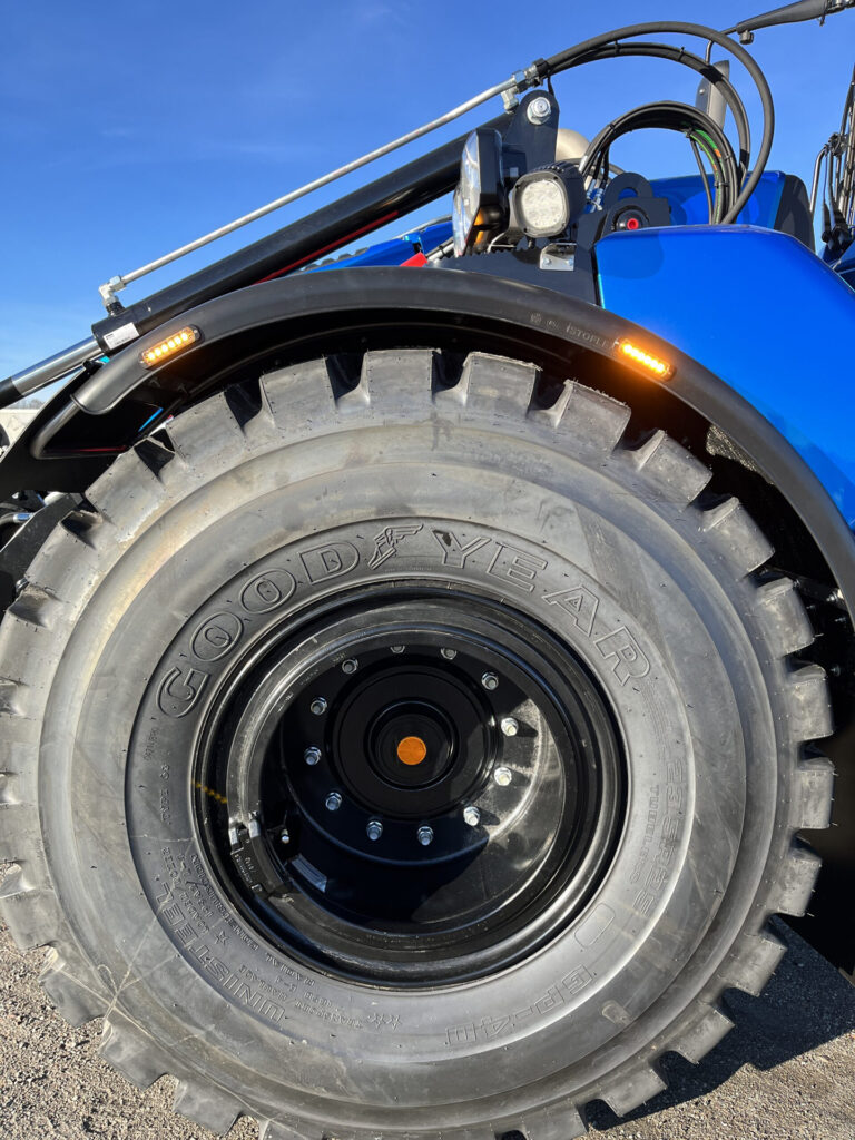 Closeup of Blue Excavator Wheel Arch with Small Amber Light Modules and Large Good Year Tyre