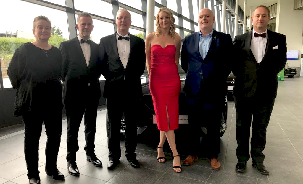 Full length shot of six people in evening wear in forecourt of exhibition hall