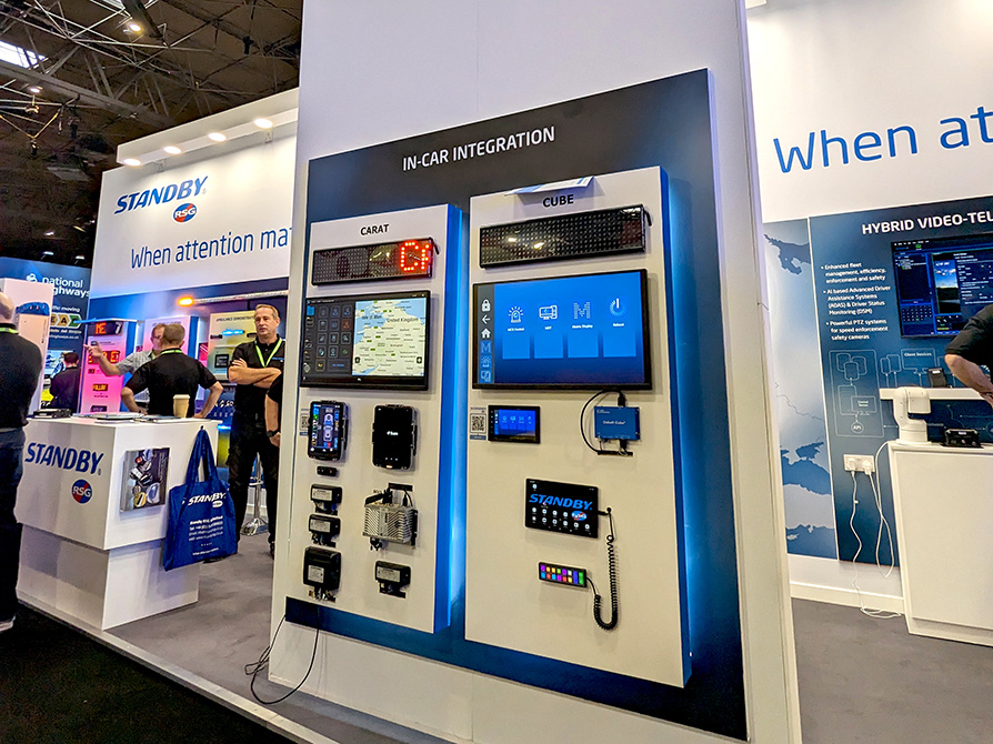Standby RSG stand at The Emergency Services Show 2023 with groups of people crowded around, focus on the centre pillar with 'In-Car Integration' products and screens