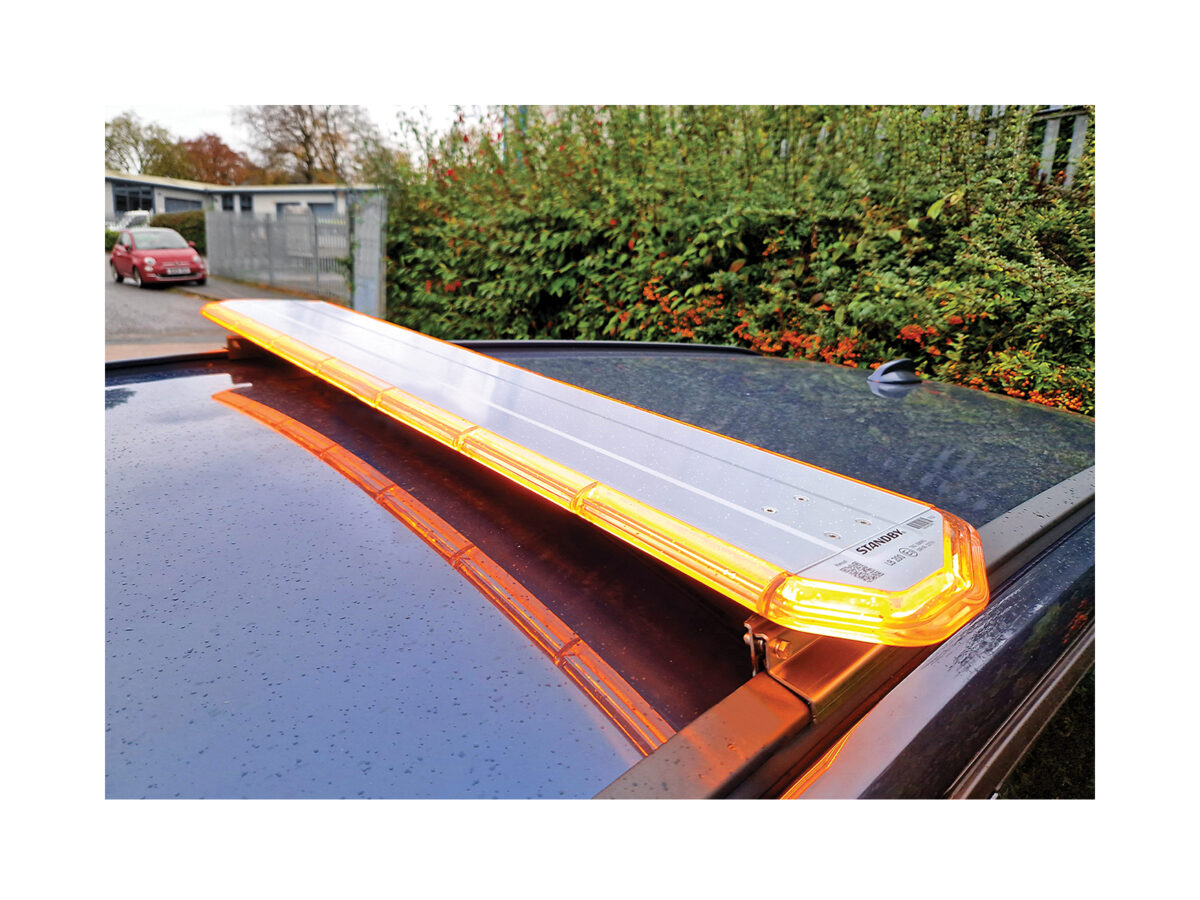 LB200 Amber angle view in situ on dark car roof in front of hedge and metal gates.