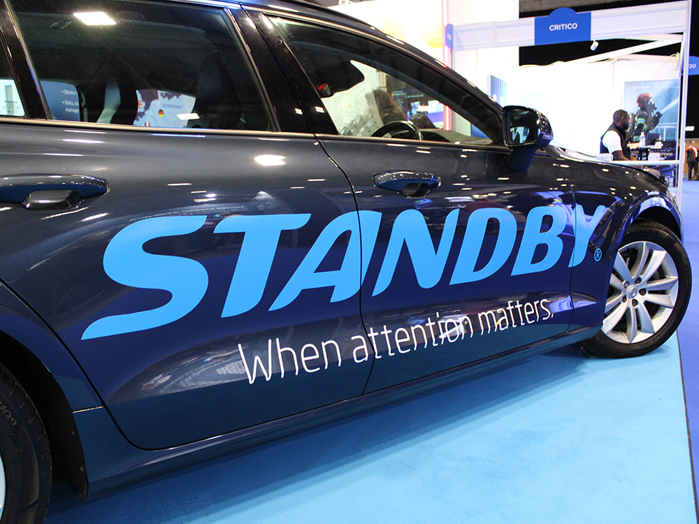 Close up angle shot of dark grey car with 'Standby - When attention matters.' livery.