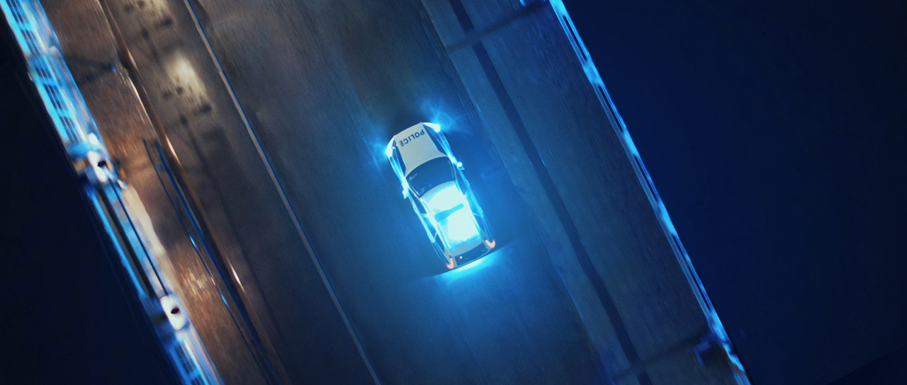 Aerial view of Police Car crossing lit up bridge at night