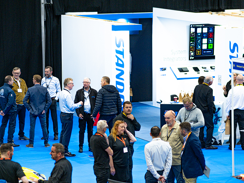 Far view of the Standby exhibition stand with show attendees standing in the foreground.