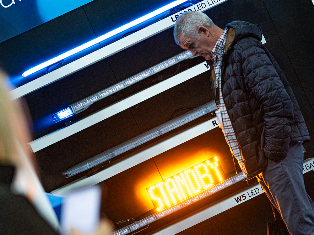 Angle view of a man standing side on to a wall of lightbars, one has an Amber sign lit up on top which reads 'Standby'