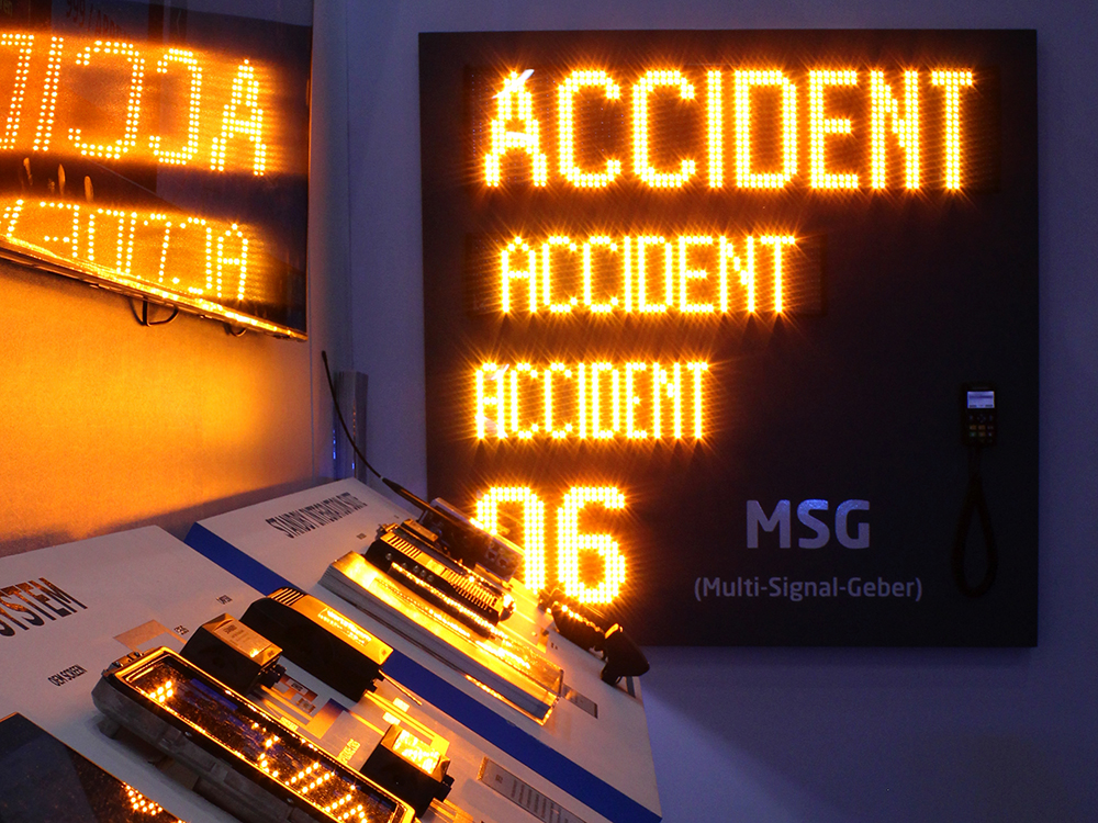 Closely cropped shot of a multi matrix display which repeats the word 'Accident' in amber 3 times, followed by '06'. The lights reflect off of nearby screens. The picture is very dark except for these lights.