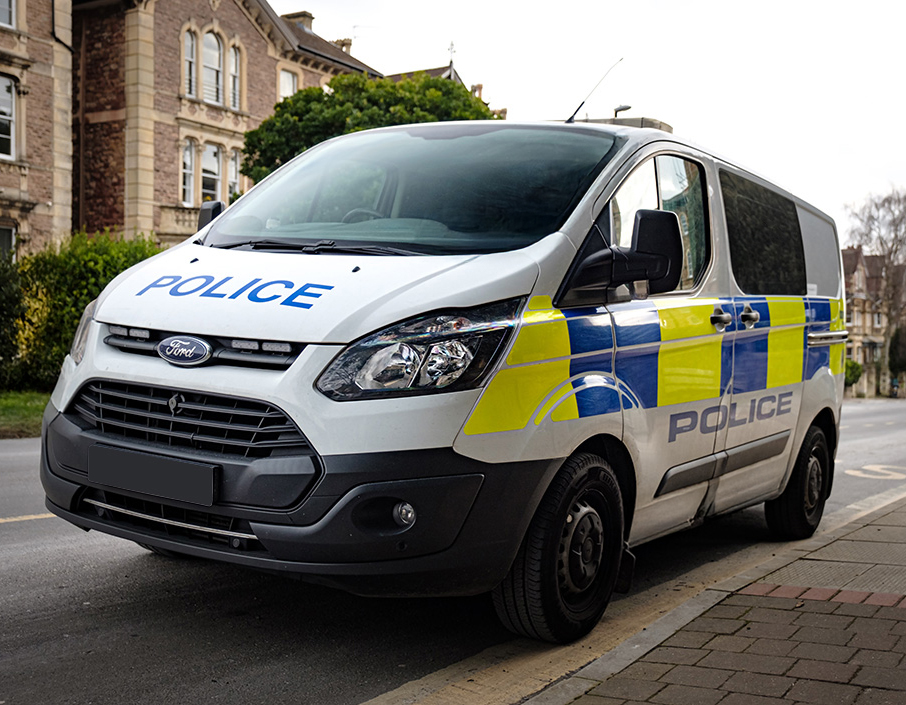 Police Cell Van parked on curb on street with townhouses in the background