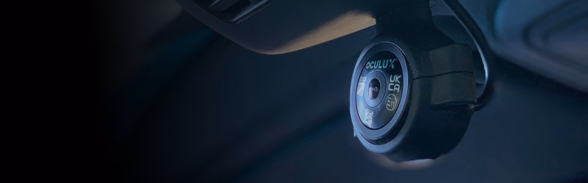 Close up of Oculux Camera in Pedestal Mount Attached to headliner in vehicle, facing the windscreen, looking out to black gradient.