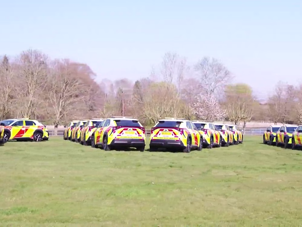 Fleet of Toyota BZ4Xs National Highways vehicles parked in lines of opposing angles in a field.