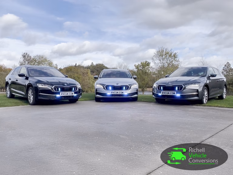 3 x Richell Vehicle Conversions Skoda Octavia Driver Training Vehicles parked on grass at opposing angles past a concrete surface with blue lights lit.