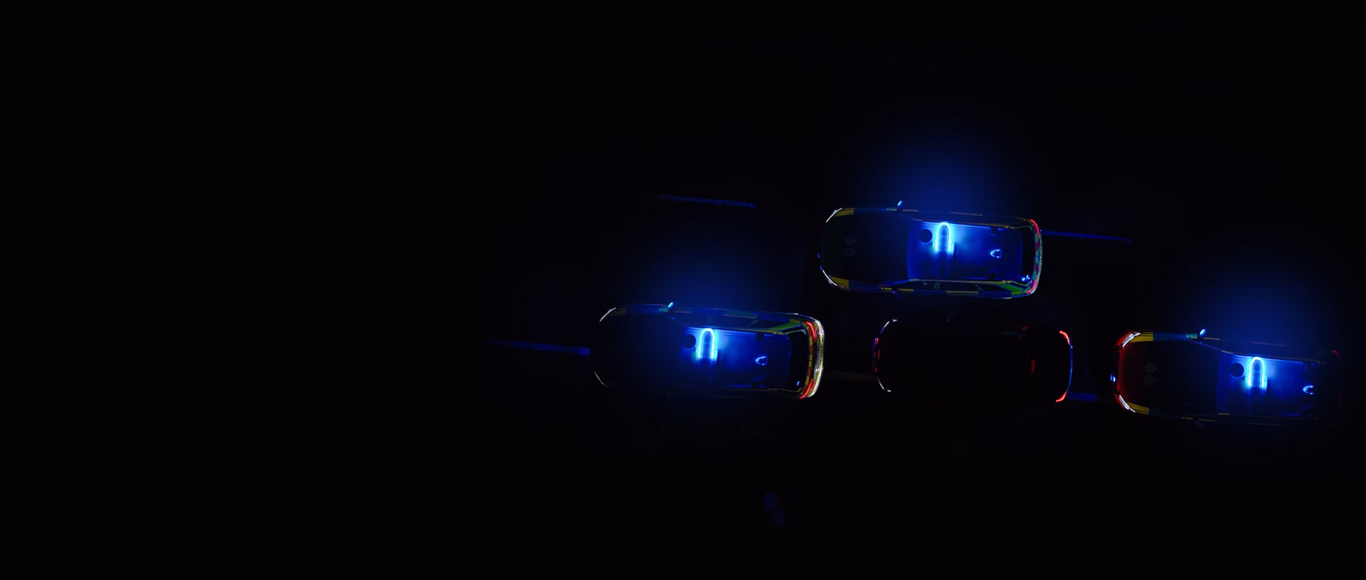 Dark drone shot above 3 Police vehicles T-packing a passenger vehicle. Their lightbars are in sync.