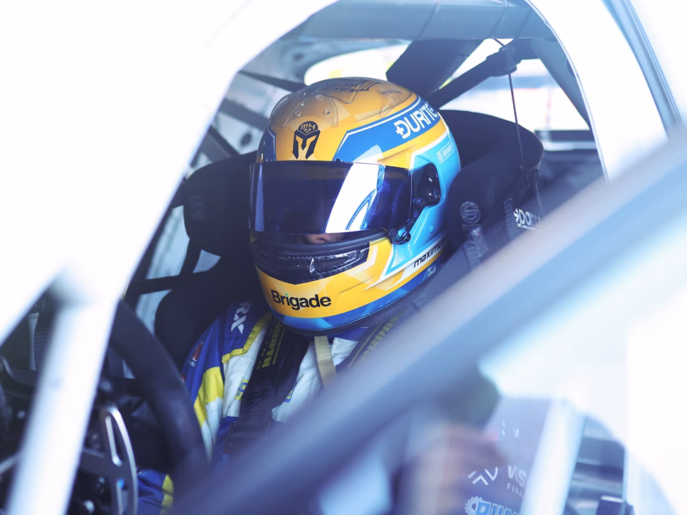Close up shot of race driver Max Hall in racing helmet seen through an open car door