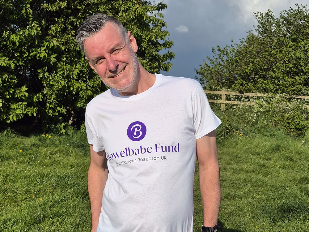 Standby UK's General Production Operative Darren Challinor wearing a white Bowelbabe tshirt and running gear, upper torso shot in a sunny field
