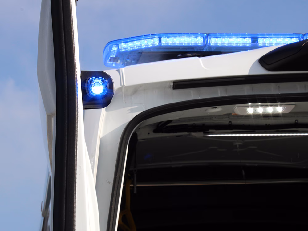 Closely cropped shot of a HM Coastguard Ford Transit OSV taken of the rear upper corner, showing the Raiden LED Lightbar and Pop-n-Lock on the open back door, both lit in blue.
