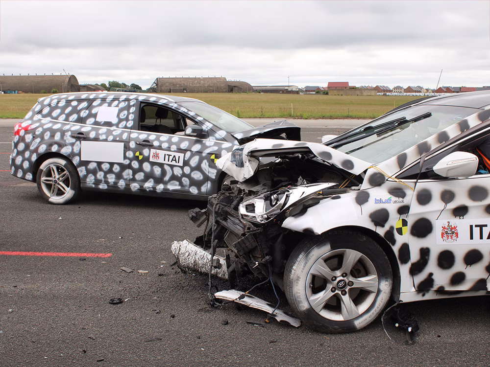 Staged crash of black and white vehicles with contrasting spray painted spots and heavily damaged front ends taken on an airfield runway at ITAI Crash Day 2026
