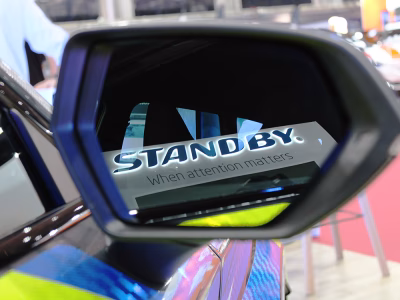 Closely cropped view of a vehicle wing mirror, reflecting the lit up Standby sign with 'When attention matters' tagline on the Standby stand at NAPFM 2026.