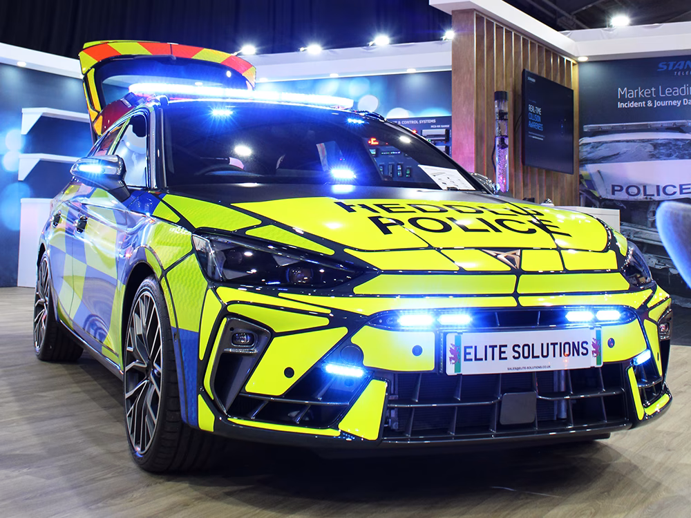 South Wales Police Cupra Leon Estate RPU converted by Elite Solutions with full Standby kit and Elite Solutions license plate, parked on the Standby UK stand at NAPFM 2026. The boot is up and emergency lighting activated.
