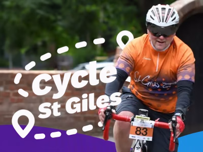 Man in orange St Giles cycle gear on a racing bike cycles towards the camera against a leafy background, Cycle St Giles graphics overlayed.